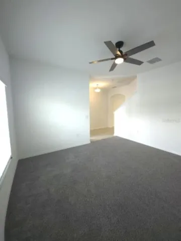 an empty room with a window and a fan