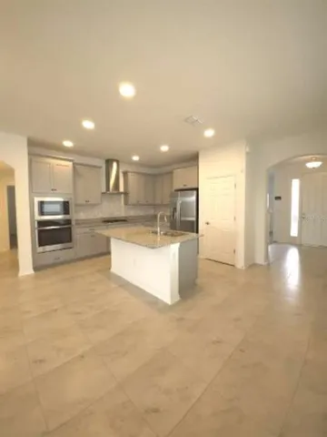 a large kitchen with kitchen island a stove a refrigerator a sink and a oven