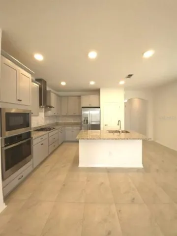 a large kitchen with kitchen island a stove a sink and a refrigerator