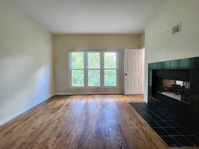 an empty room with wooden floor fireplace and windows