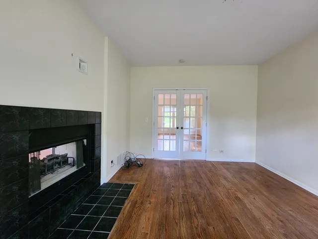 a view of an empty room with wooden floor fireplace and a window