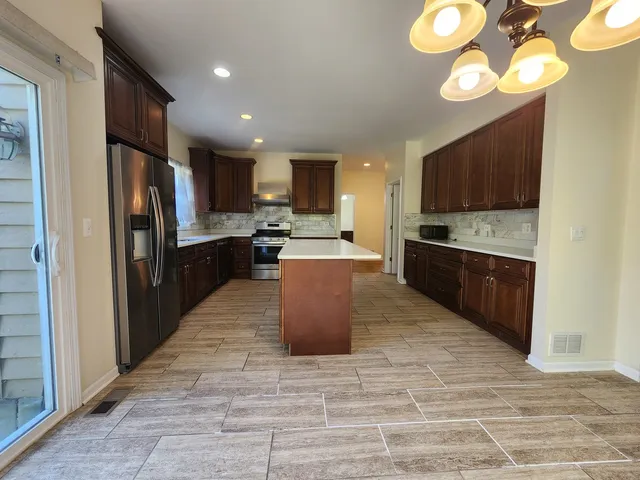 a kitchen with stainless steel appliances granite countertop a refrigerator a stove top oven a sink and dishwasher