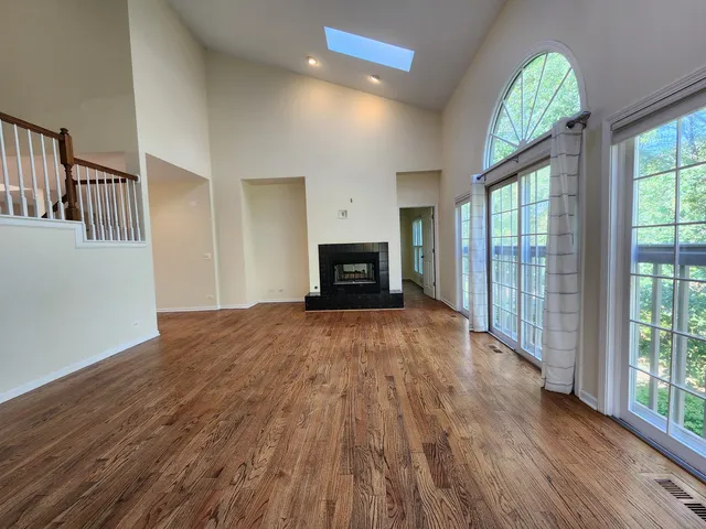 an empty room with windows fireplace and wooden floor