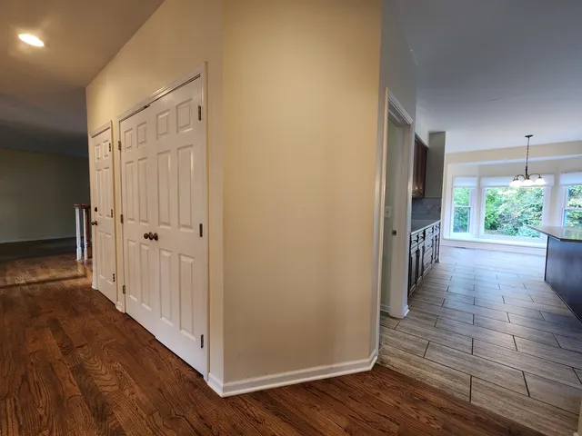a view of a hallway with wooden floor and closet area