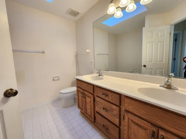 a bathroom with a double vanity sink a toilet and a mirror