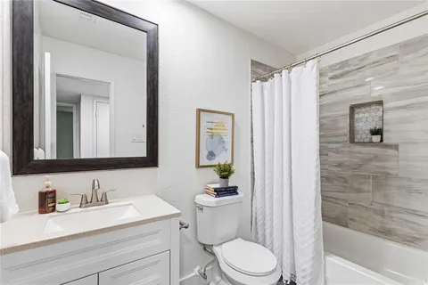 a bathroom with a granite countertop sink toilet a mirror and shower