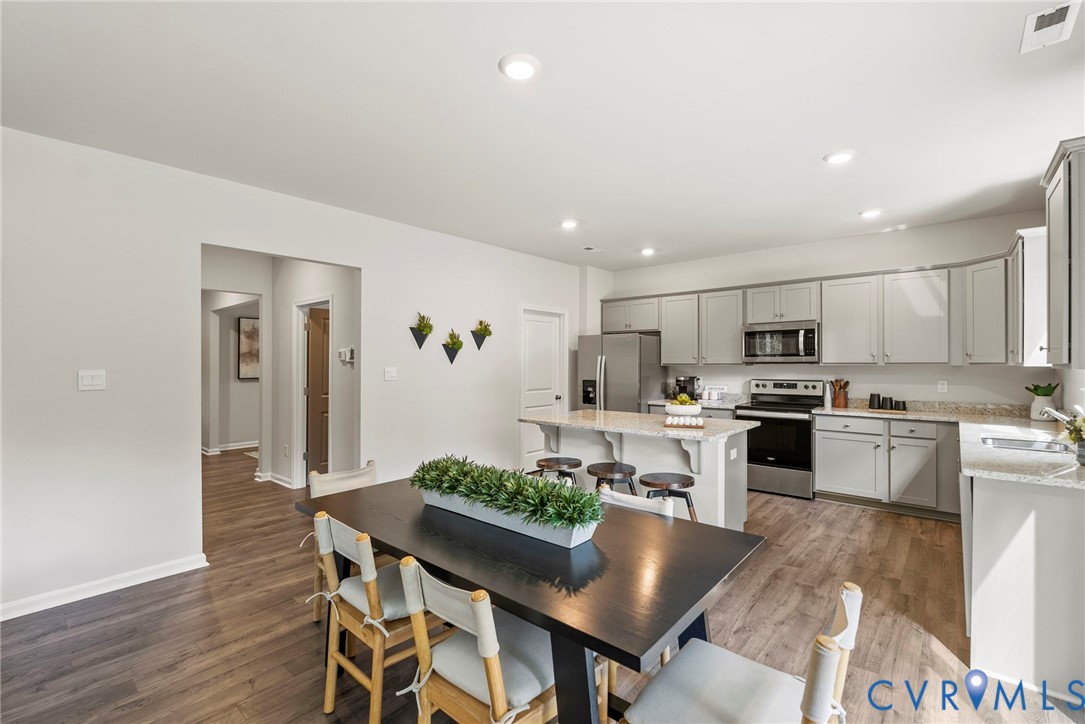 7745 Arbor Marsh Terrace New Kent, VA 23124 - Photo 2 of 30 a kitchen with white cabinets stainless steel appliances and dining table