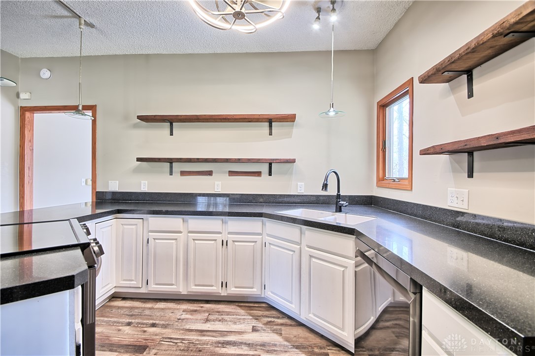 8711 Nicole Lane Springboro, OH 45066 - Photo 14 of 87 This kitchen features sleek black countertops and stylish white cabinetry with wood plank flooring.