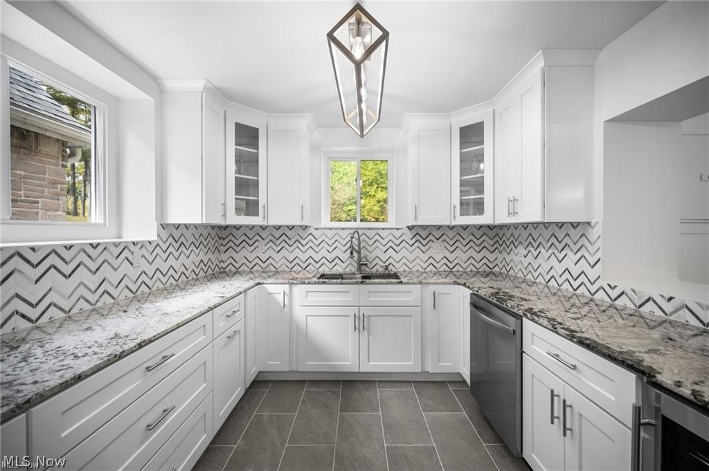 28300 Aurora Road Solon, OH 44139 - Photo 3 of 36 Kitchen featuring white cabinetry, stone countertops, a chevron-patterned backsplash, stainless steel dishwasher, and dark tile flooring