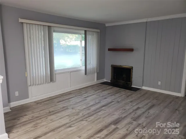 an empty room with wooden floor fireplace and windows