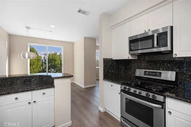 a kitchen with stainless steel appliances granite countertop a stove and a microwave