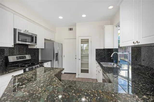 a kitchen with stainless steel appliances kitchen island granite countertop a refrigerator and a stove top oven