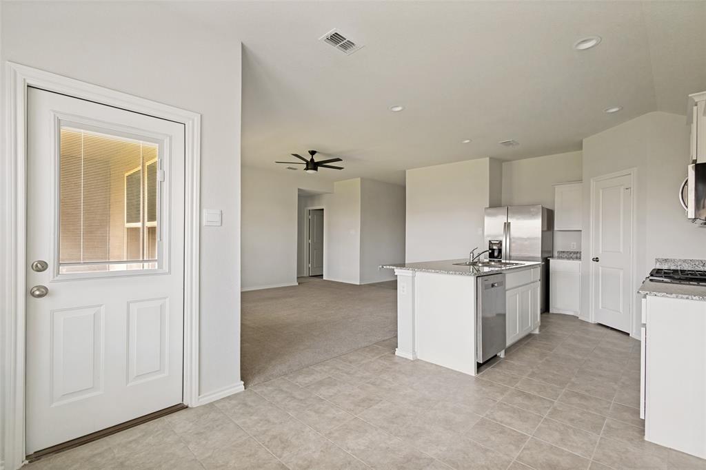621 Spaulding Street Justin, TX 76247 - Photo 4 of 22 a kitchen with refrigerator and cabinets