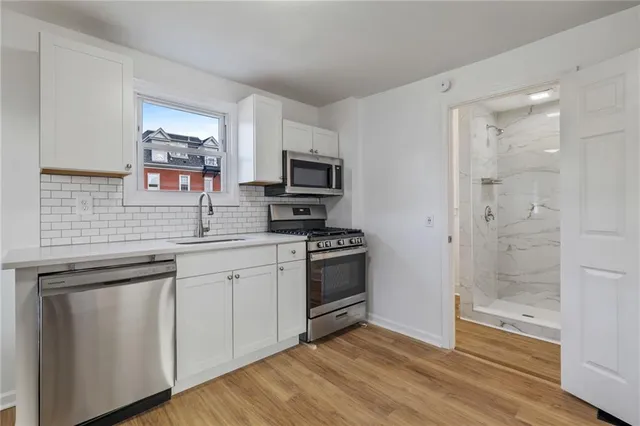 a kitchen with cabinets stainless steel appliances and wooden floor