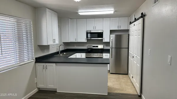 a kitchen with stainless steel appliances granite countertop a refrigerator a stove a sink and white cabinets