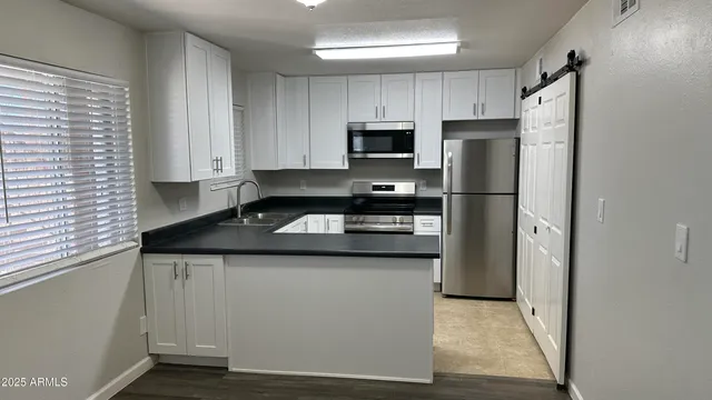 a kitchen with stainless steel appliances granite countertop a refrigerator a stove a sink and white cabinets