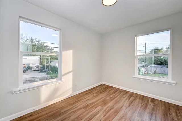 a view of empty room with wooden floor and fan