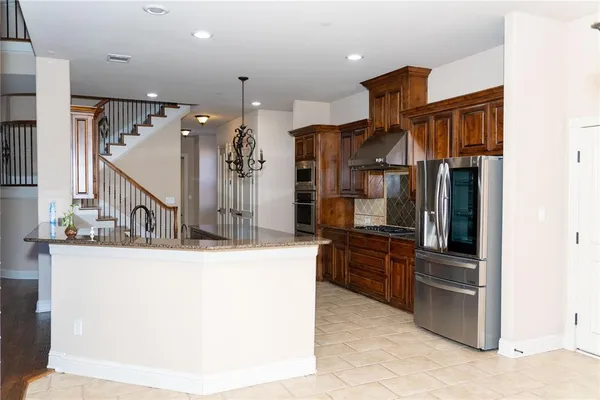 a kitchen with stainless steel appliances kitchen island granite countertop a refrigerator and a sink