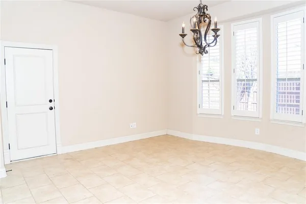 an empty room with windows and chandelier fan