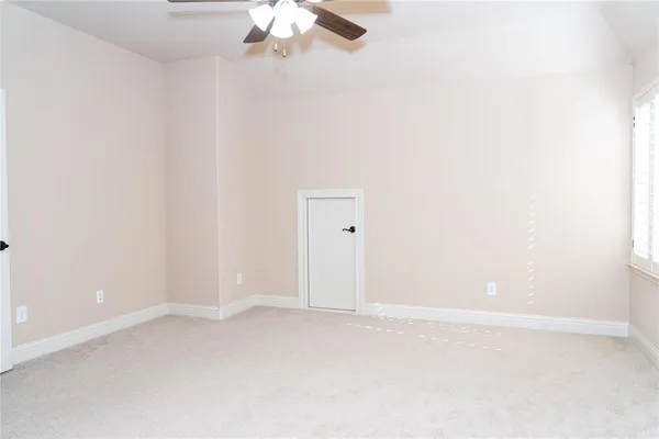 an empty room with chandelier fan and windows