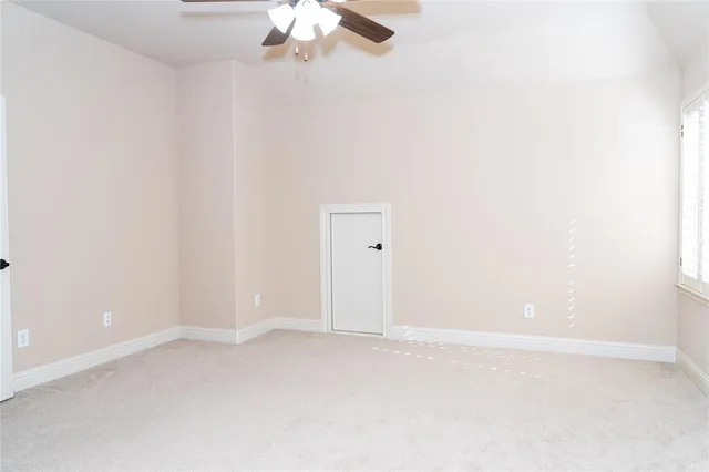 an empty room with chandelier fan and windows