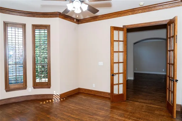 an empty room with wooden floor fan and windows