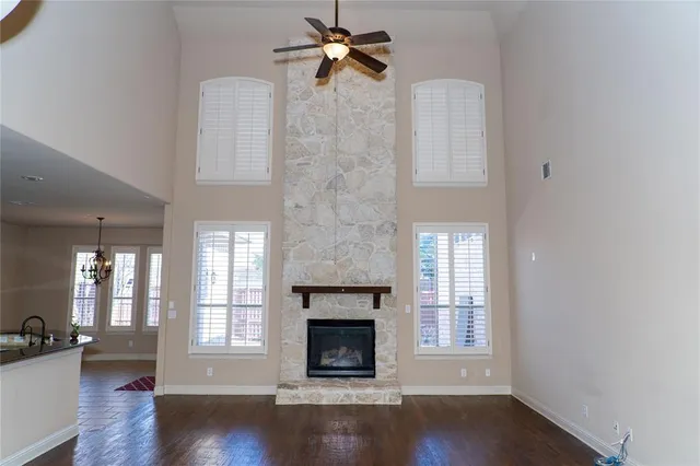 an empty room with wooden floor fireplace and windows