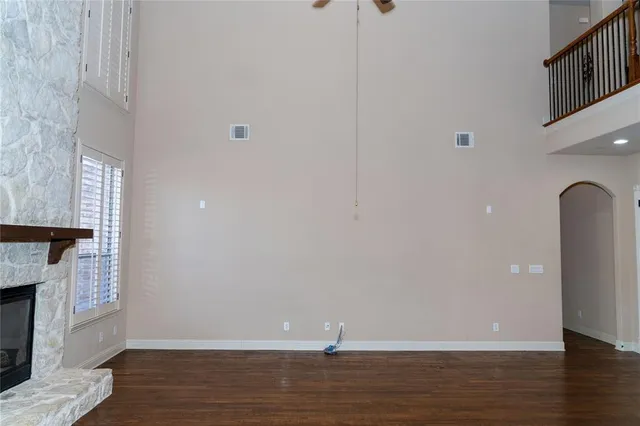 a view of an empty room with wooden floor and a fireplace