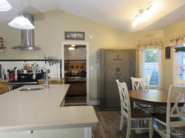 a kitchen with stainless steel appliances granite countertop a refrigerator a sink dishwasher a stove and a dining table with wooden floor