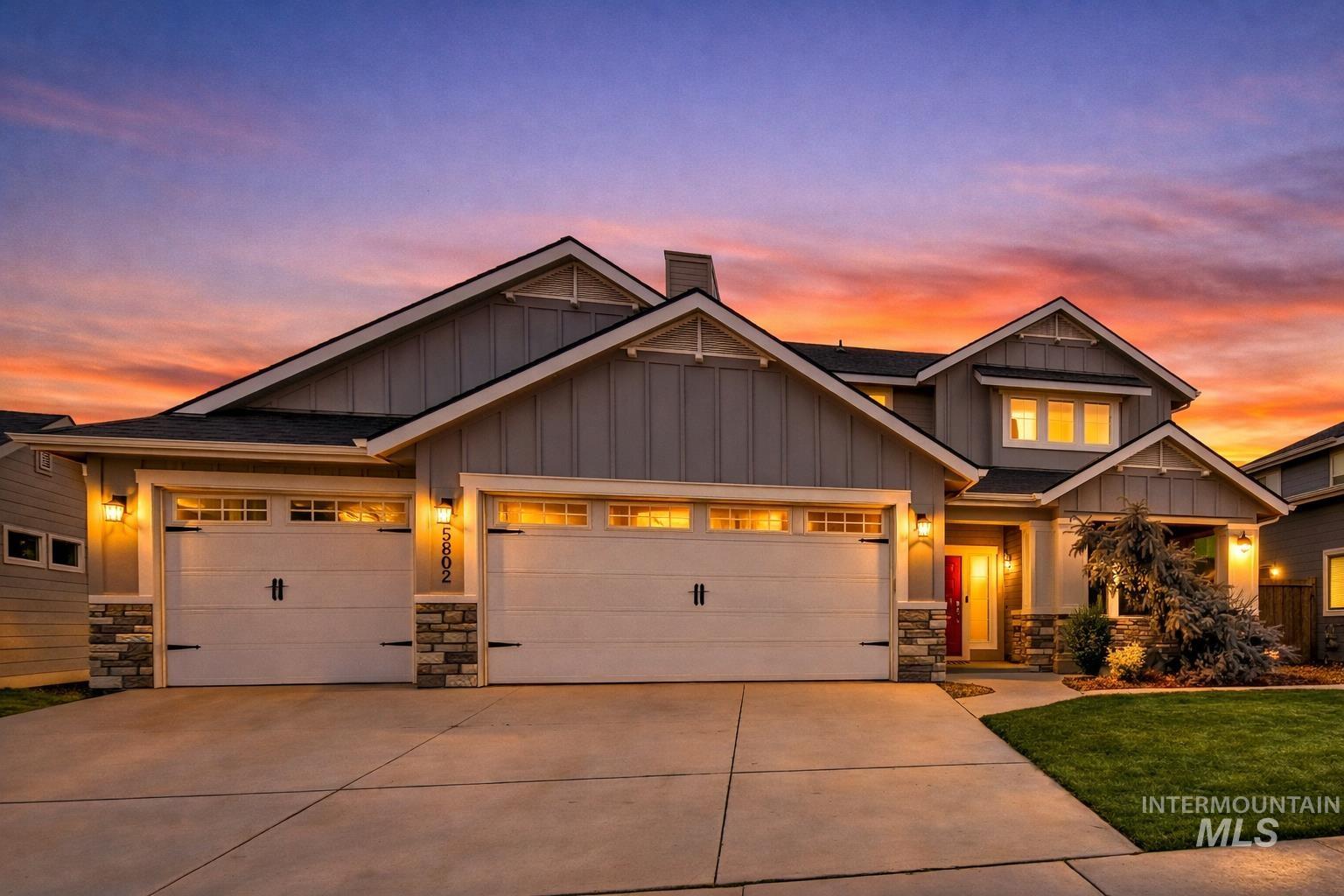Craftsman-style home featuring board and batten siding, a garage, concrete driveway, stone siding, and a chimney