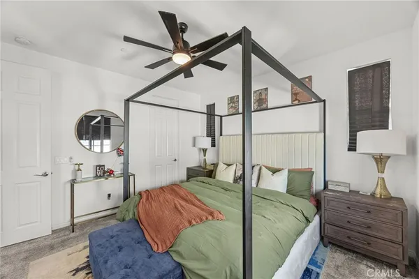 a bedroom with a bed a lamp on dresser and a chandelier