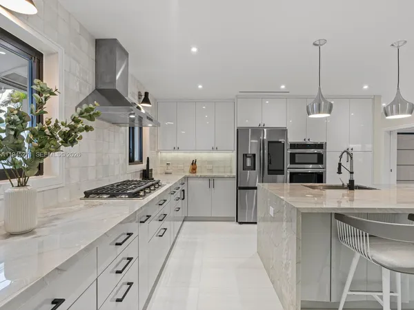 a kitchen with stainless steel appliances kitchen island a stove a sink a refrigerator and a counter top space