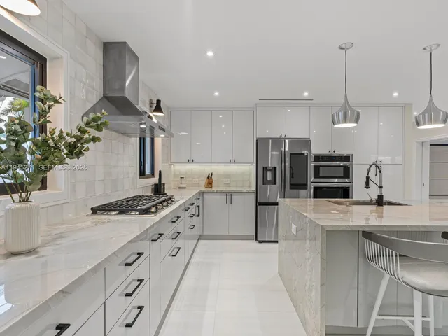 a kitchen with stainless steel appliances kitchen island a stove a sink a refrigerator and a counter top space