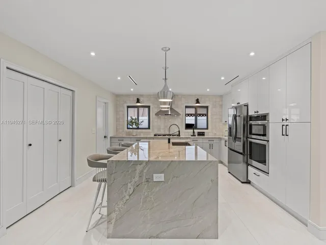 a large white kitchen with a large window and stainless steel appliances