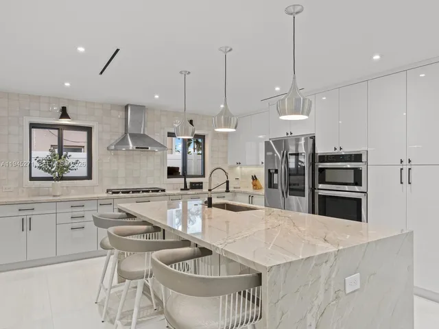 a kitchen with stainless steel appliances kitchen island granite countertop a sink a stove a dining table and chairs