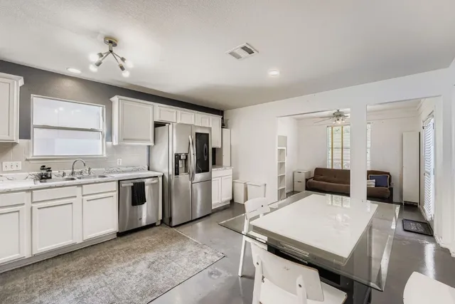 a kitchen with stainless steel appliances kitchen island granite countertop a sink a stove a refrigerator cabinets and chairs