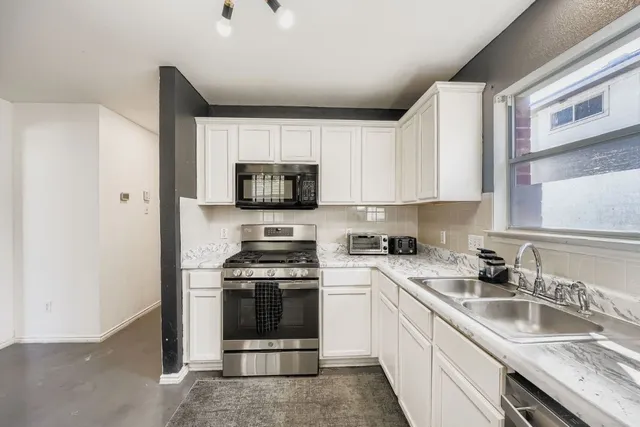 a kitchen with stainless steel appliances granite countertop a sink a stove top oven a microwave and cabinets