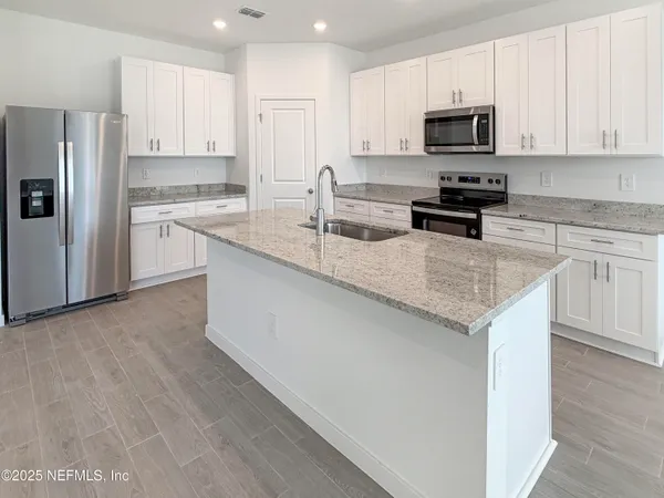 a kitchen with kitchen island granite countertop a sink a counter top space stainless steel appliances and cabinets