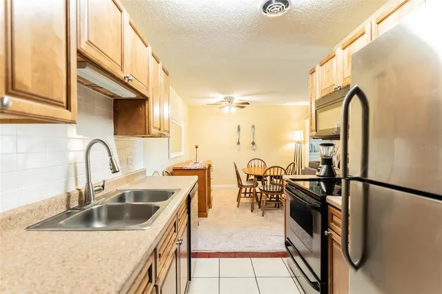 a kitchen with stainless steel appliances granite countertop a sink a stove and a refrigerator with wooden floor