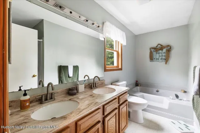 a bathroom with a granite countertop double vanity sink mirror and toilet