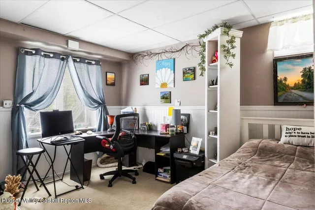 a bedroom with a bed a computer on the desk and a desk