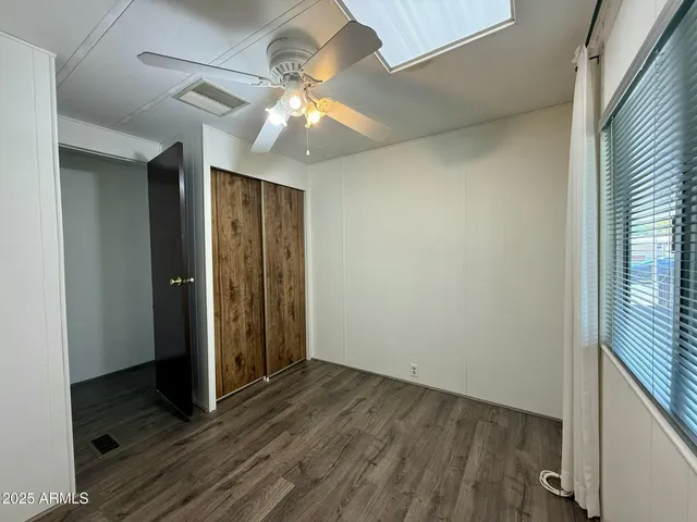 an empty room with wooden floor chandelier fan and windows