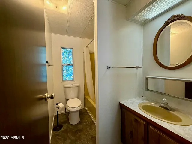 a bathroom with a granite countertop toilet a sink and a mirror