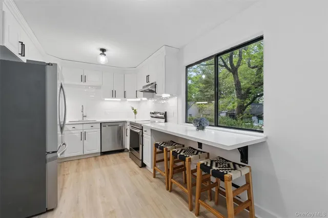 a large kitchen with kitchen island a stove a sink dishwasher a refrigerator white cabinets and wooden floor