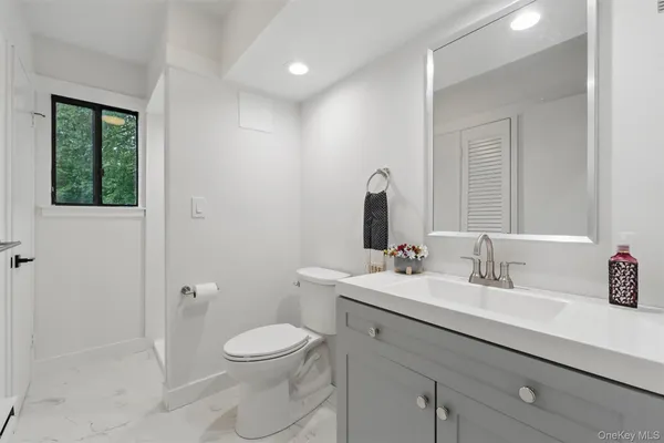 a bathroom with a toilet a sink a mirror and a shower