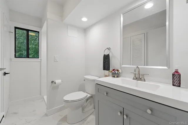 a bathroom with a toilet a sink a mirror and a shower