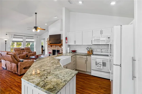 a kitchen with stainless steel appliances granite countertop a stove oven and a view of living room