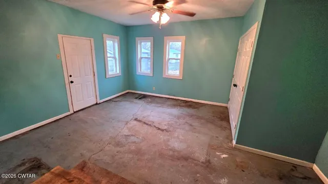 an empty room with windows and fan