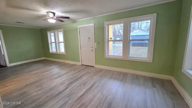 a view of an empty room with wooden floor and a window