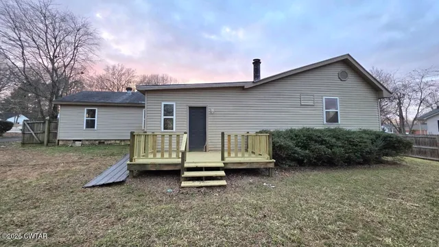 a view of a house with a yard and a large tree